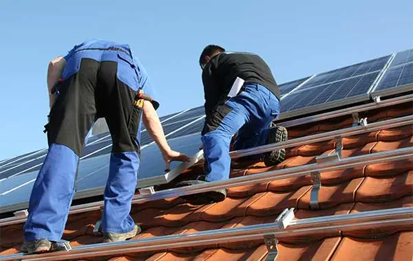 Zwei Arbeiter am Dach montieren PV-Anlage